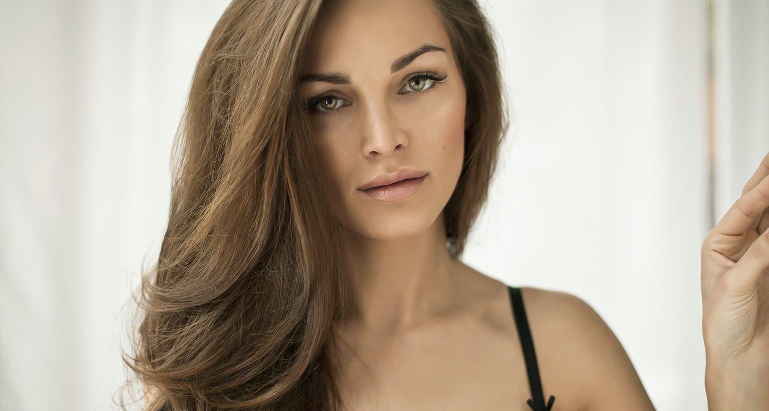 woman with brown hair and black bra looking into the camera